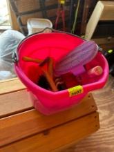 Pink bucket with horse grooming supplies.