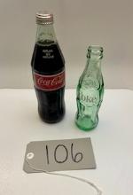 Two Classic Coca Cola Bottles, One Full 1984 and One Smaller Empty Green Glass