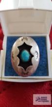 Turquoise colored stone in silver colored ring marked AI