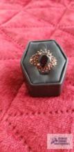 Gold colored ring with one large red stone and surrounding red stones marked 925 4.3 G (Description