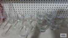 Clear glass champagne flutes and decorative raise the bar wine glasses, other assorted stemware and