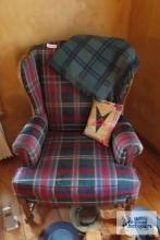 Two plaid wingback chairs. one includes blanket and decorative pillow.